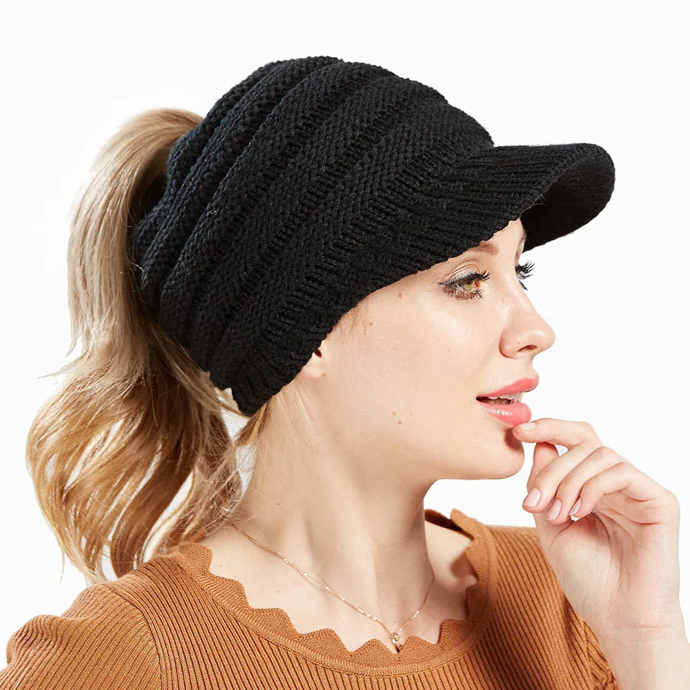 Woman wearing a thick knitted beanie with her ponytail pulled through the hole in the crown.