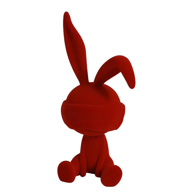 Green resin rabbit table ornament with a suede blindfold on a wooden shelf.