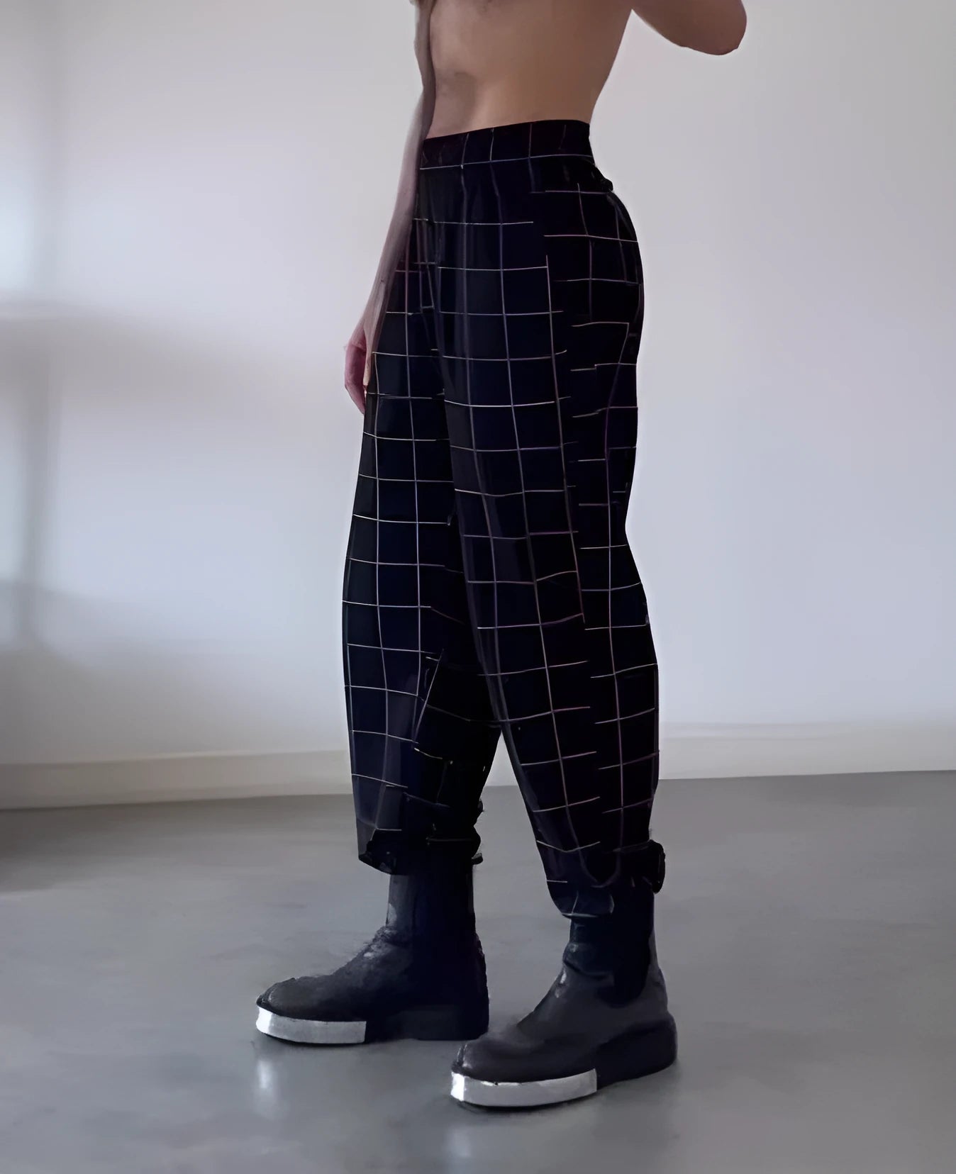 Man wearing plaid trousers with apron detailing, showing drawstring waist and multiple pockets.