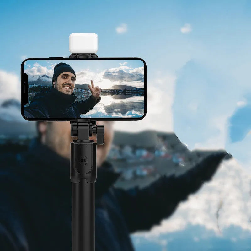 Black Bluetooth selfie stick extended from its integrated mini tripod base, holding a smartphone.