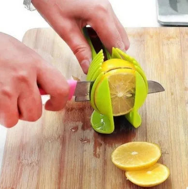 A black or green plastic tomato slicing holder on a kitchen worktop.