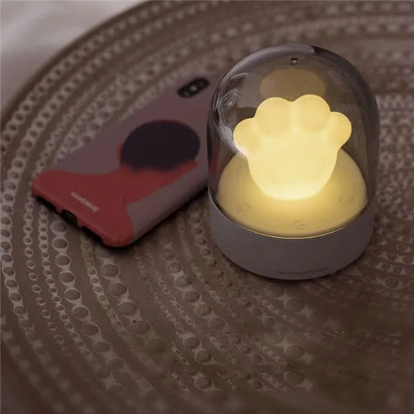 Grey cat paw shaped USB rechargeable night light with music box function on wooden desktop