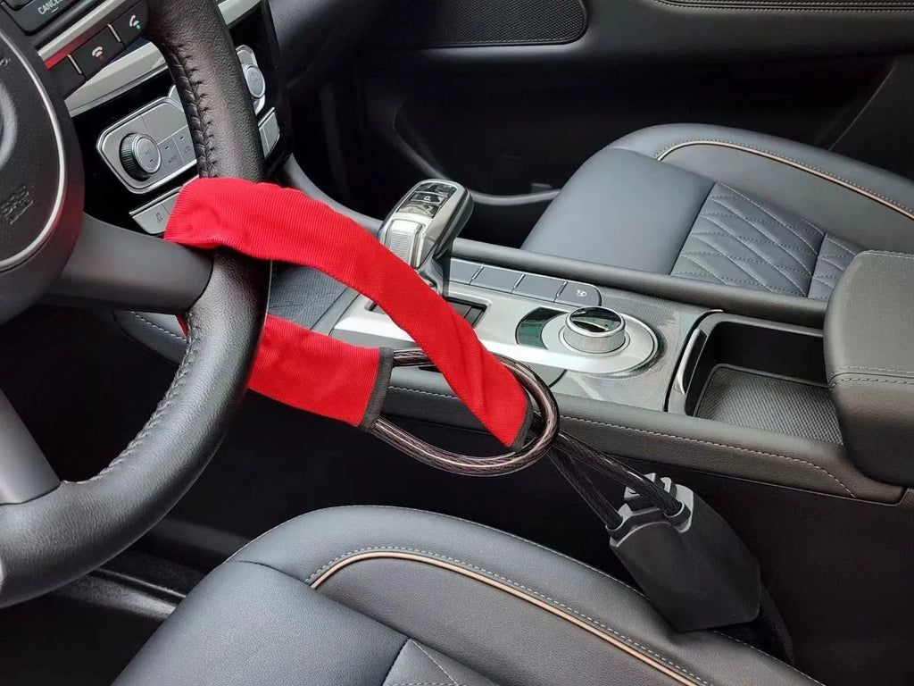 Red iron cable car steering wheel lock for General Motors vehicles on a black steering wheel.