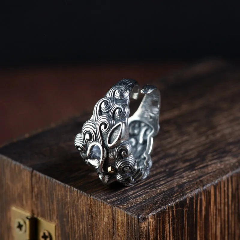 Silver open ring with detailed Jibeast and zodiac animal pattern, shown on a hand.