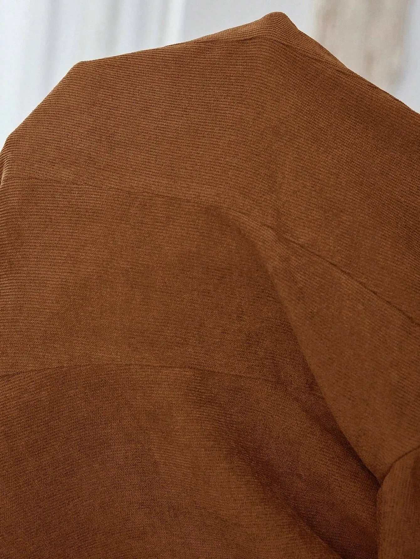 Brown men's single-breasted lapel blazer with long sleeves on a hanger.