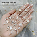 Mixed silver alloy metal nail art pendants with tassel and pearl accents on white background