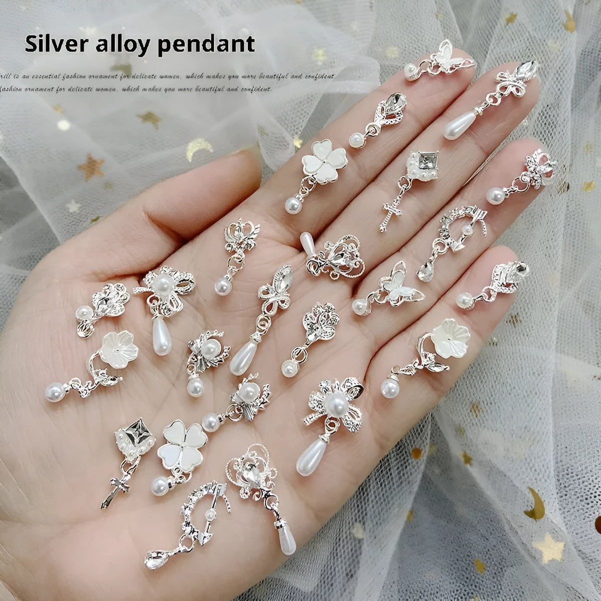 Mixed silver alloy metal nail art pendants with tassel and pearl accents on white background