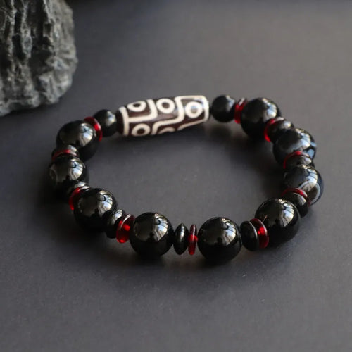 Close-up of a hand-woven black agate dzi bead bracelet with 11mm geometric beads on a wrist.