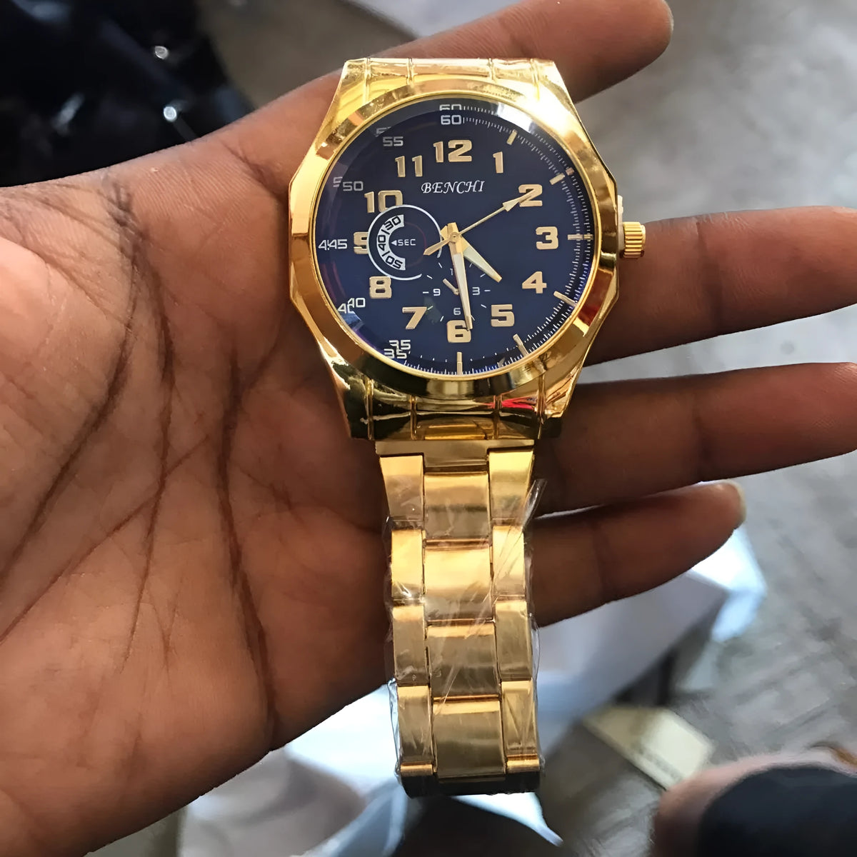 Gold-tone analog watch with round dial and metal link bracelet on a white background
