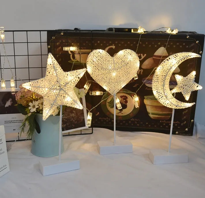 Rattan woven star-shaped LED table lamp with copper wire details on a table.