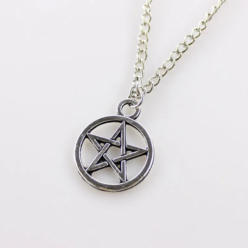 Vintage pentagram necklace on alloy adjustable chain, bronze finish, lying flat on grey surface