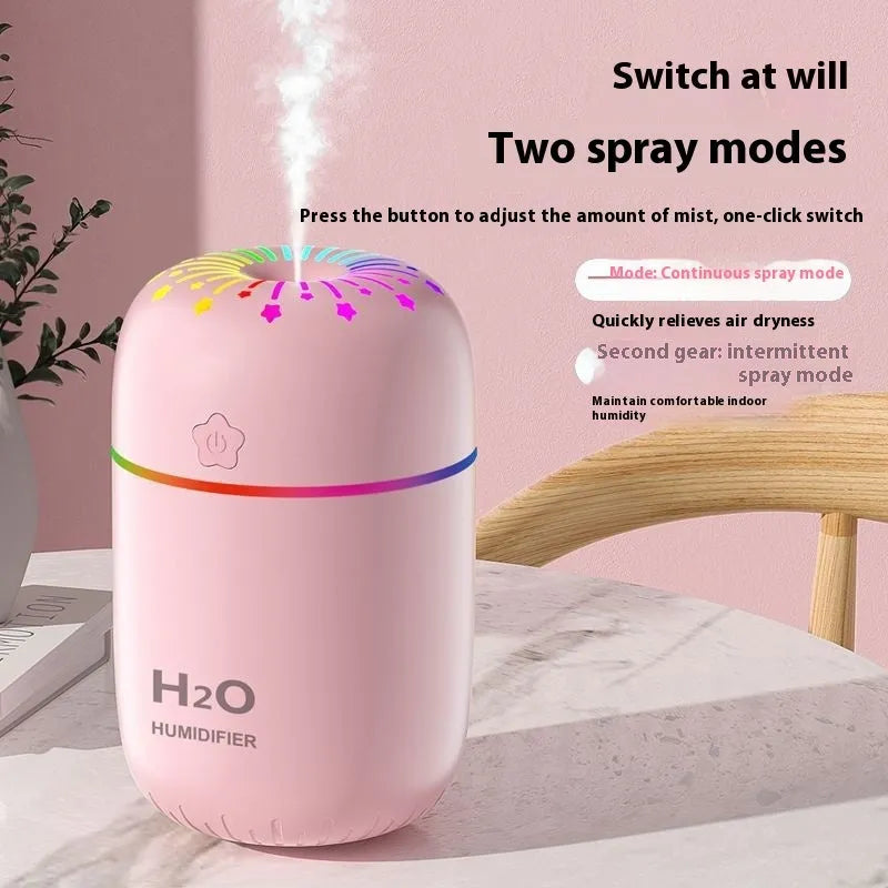 White USB mini humidifier with water tank on a desk next to a laptop