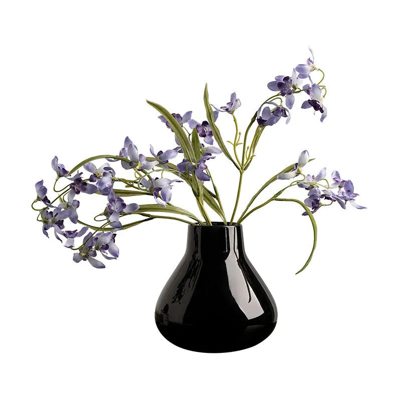 Black ceramic round belly vase with white orchid flowers on wooden shelf