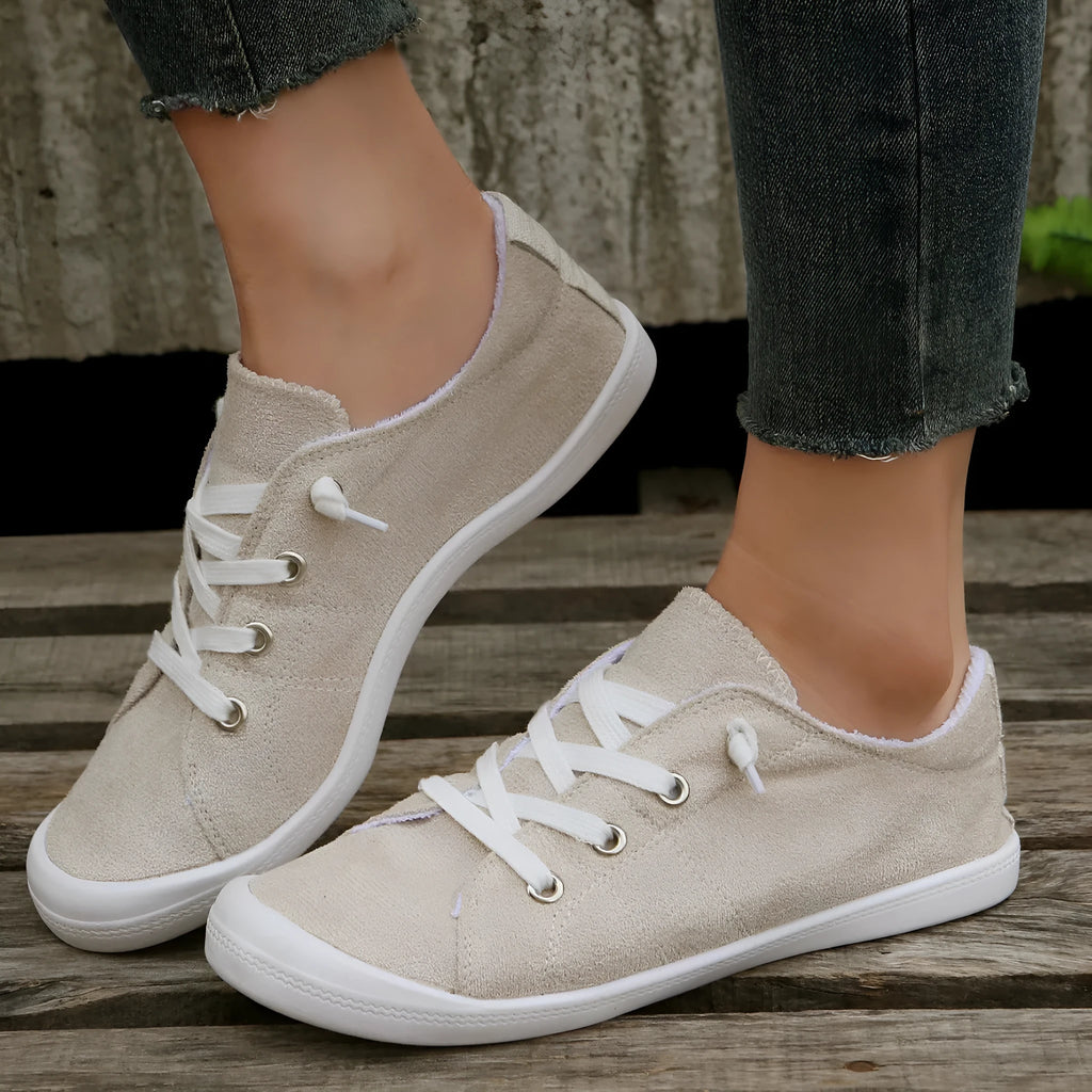 Women's creamy white low-top fabric casual sneakers with a rubber sole on a neutral background.