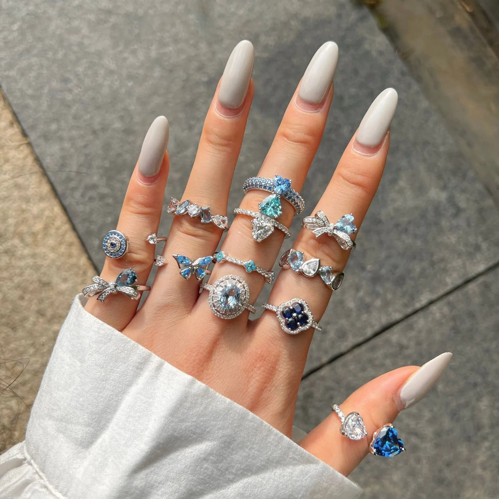 Women's S925 sterling silver ring with sea blue zircon heart or bow shape on plain background