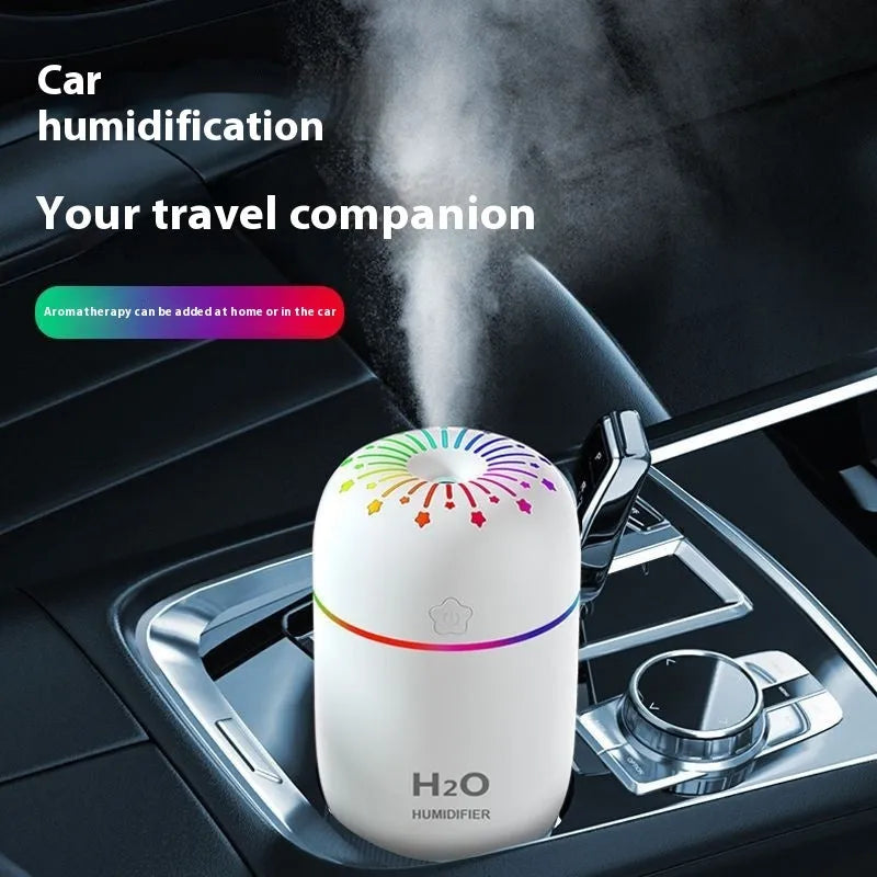 White USB mini humidifier with water tank on a desk next to a laptop