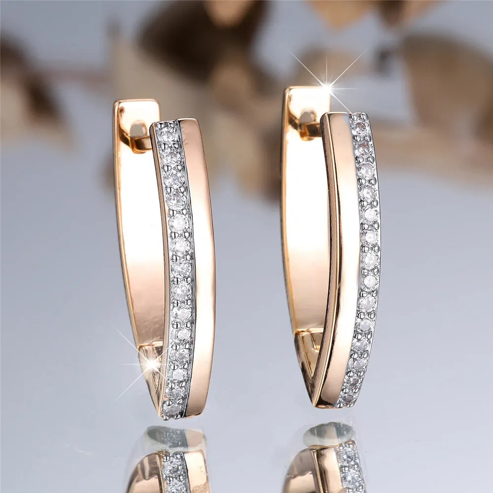 Women's geometric V-shape ear clips in champagne gold with white diamond detail on copper construction