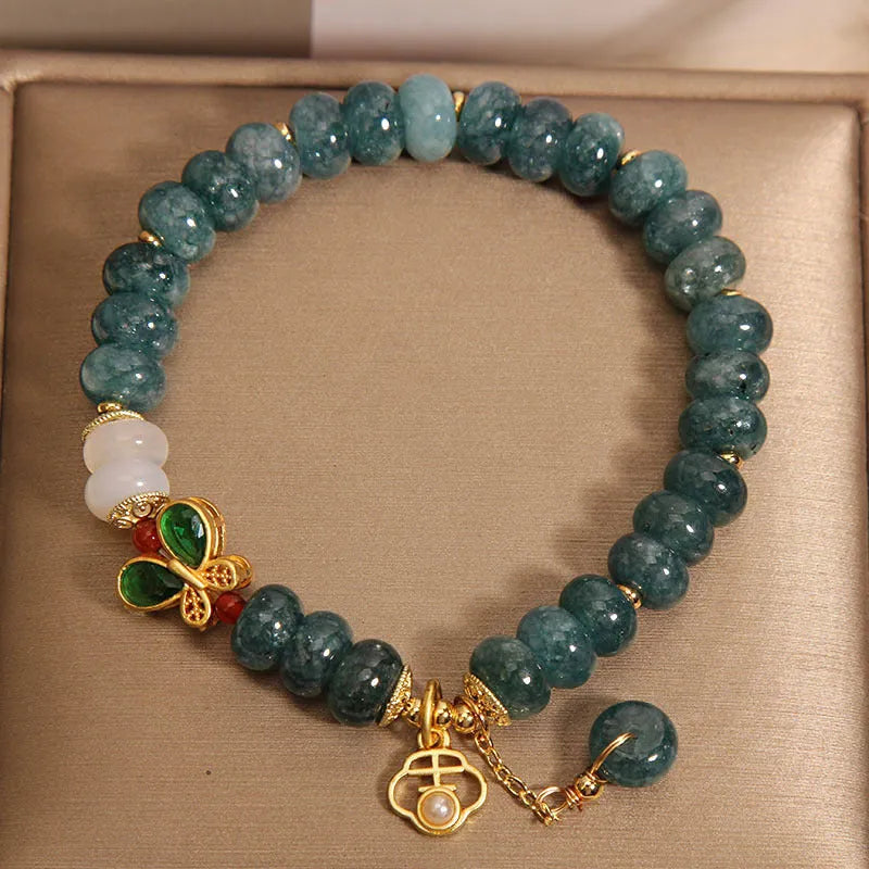 Blue water jade abacus beads bracelet with white agate, butterfly motifs and rhinestone accents on alloy band