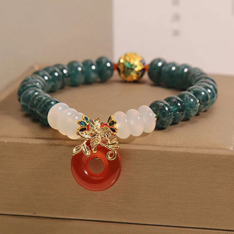 Close-up of a women's crystal bracelet with blue jade beads, red agate, and a silver peace buckle closure.