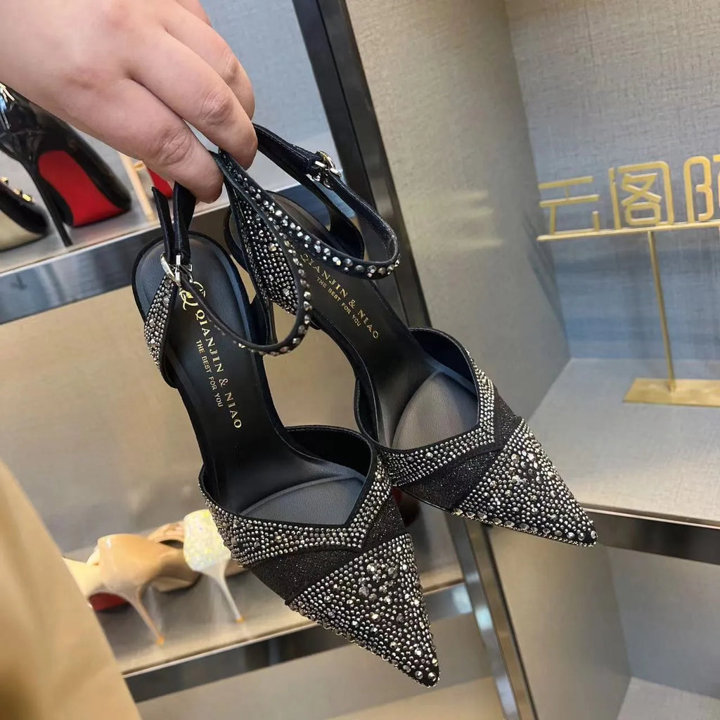 Women's black high heel shoe with a red sole, pointed toe, and a hollow stiletto heel on a plain background.