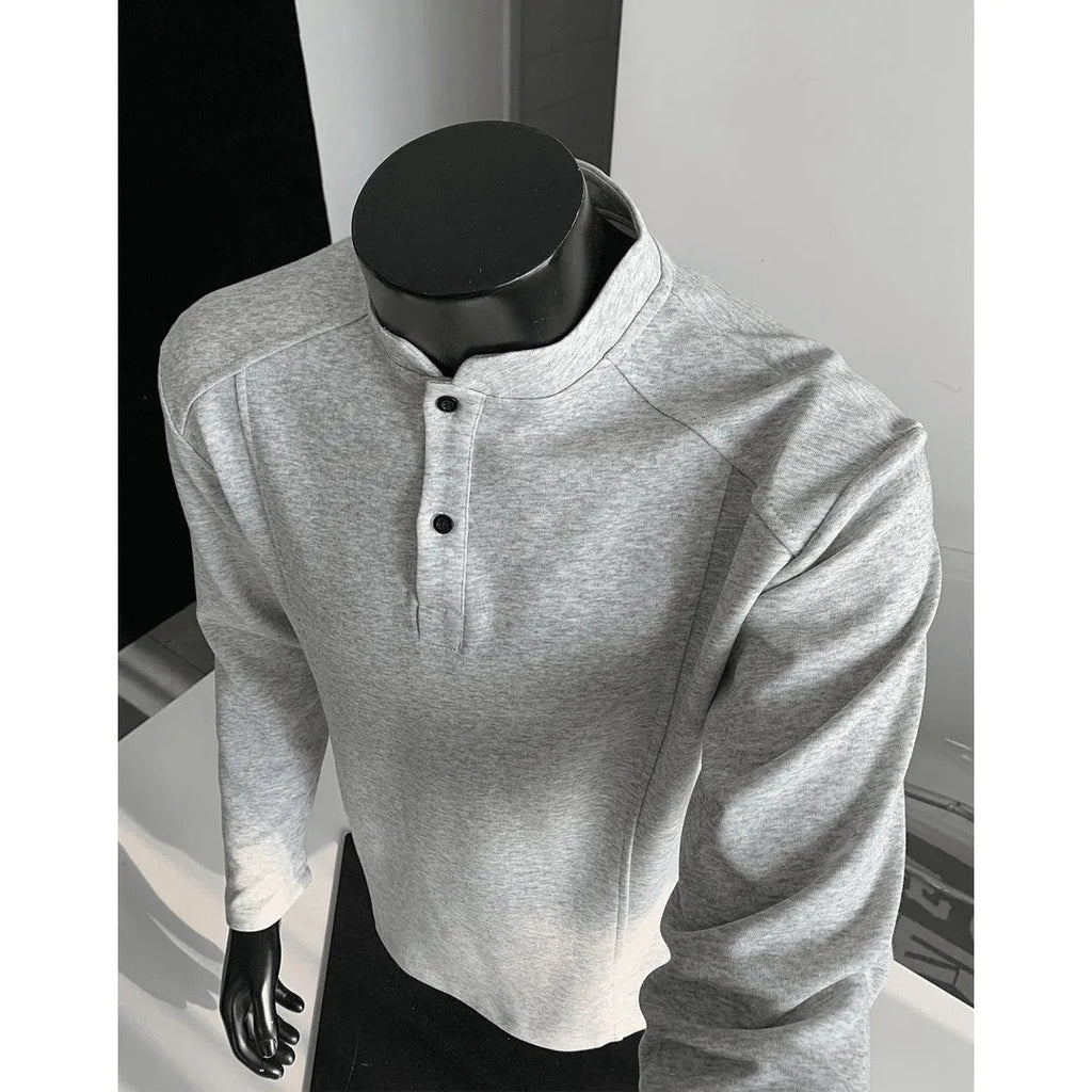 Men's black asymmetric patchwork long sleeve polo shirt with a stand-up collar, laid flat.