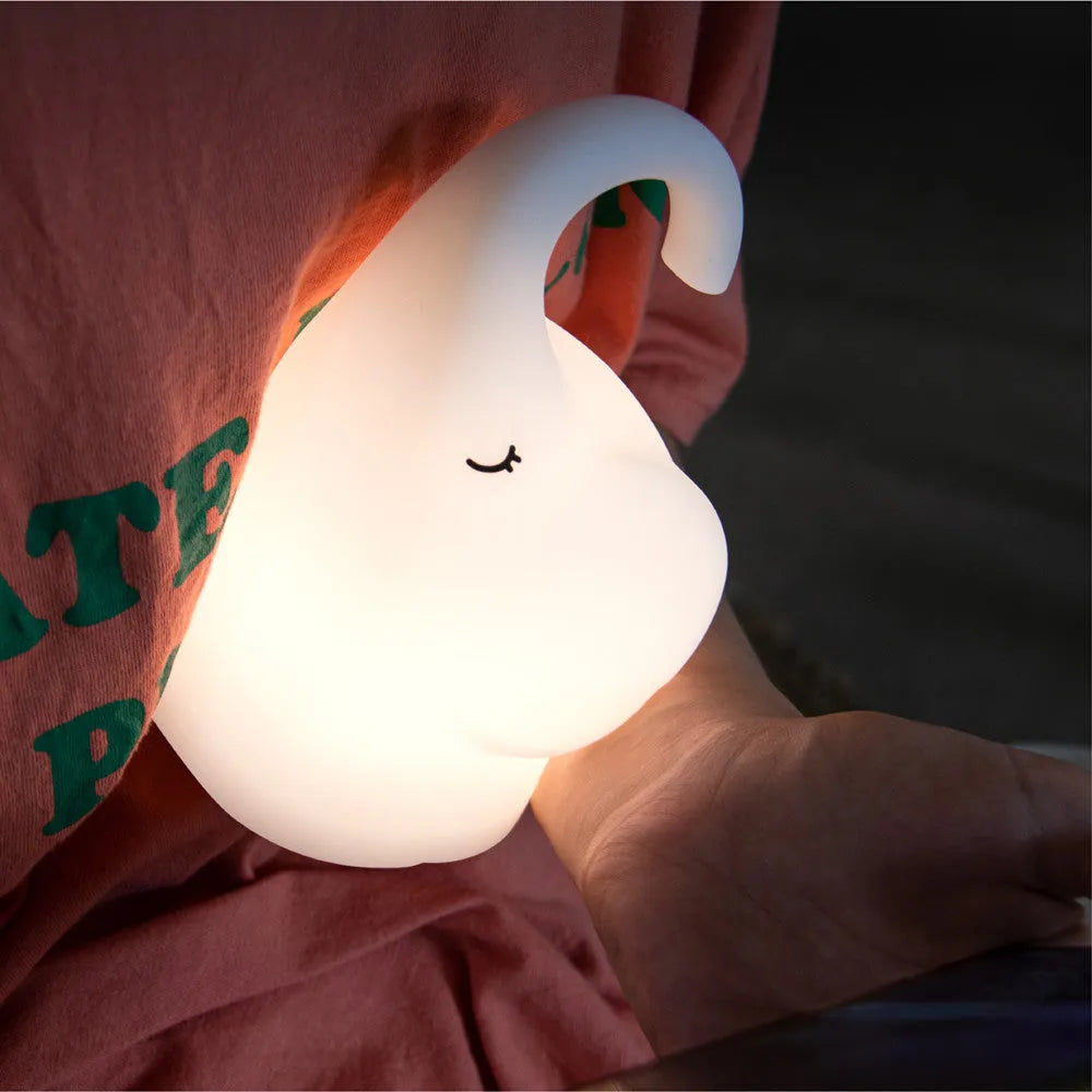 DOMI Elephant shaped silicone night light with warm white LED glow on a bedside table.
