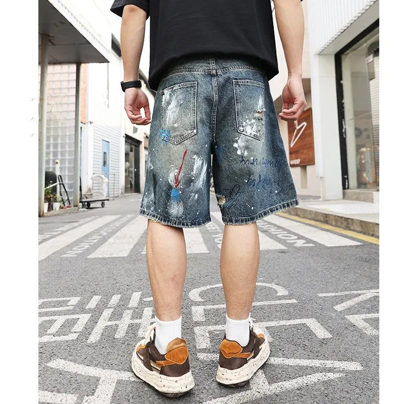 Blue denim shorts for men with rips and a graffiti pattern, featuring a zipper fly.