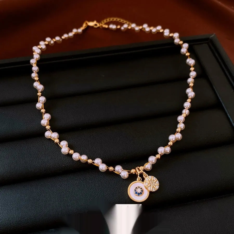 Gold-white electroplated necklace with round imitation pearl and zircon pendant on an adjustable clavicle chain.