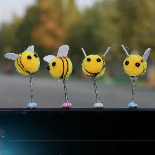Small yellow and black fur ball bee car decoration on a plastic surface.