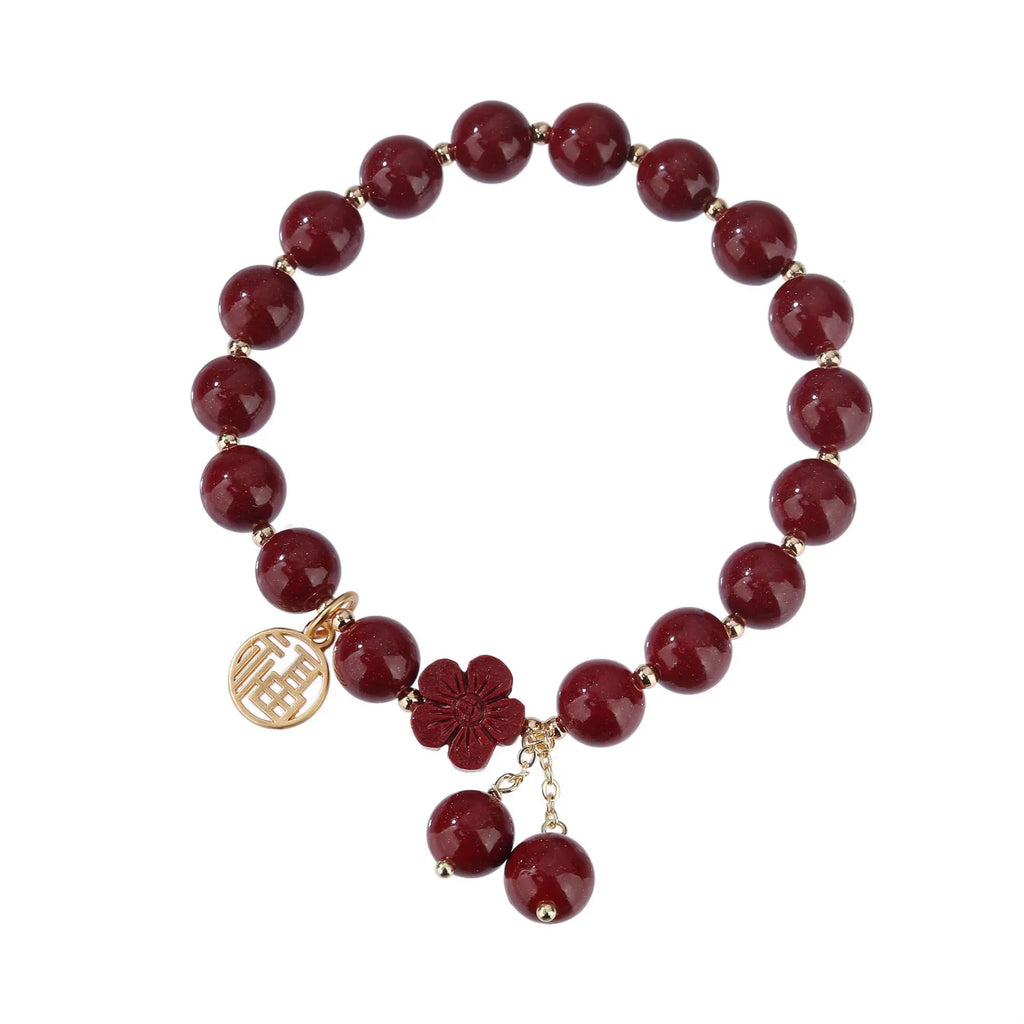 Close-up of a retro-style women's cinnabar bracelet with purple gold sand colour, showing fu character design and tassels.