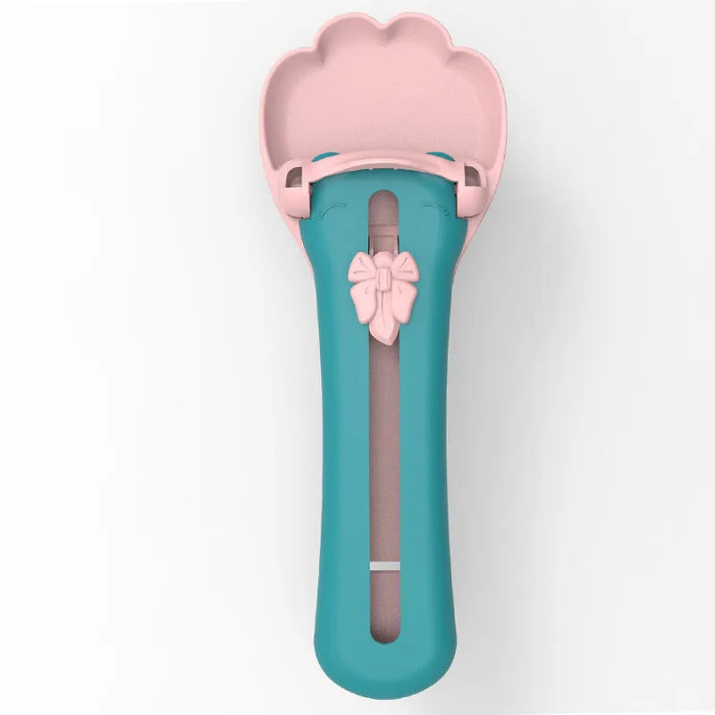 Green and pink pet food spoon squeezer feeder for dispensing kibble and treats.