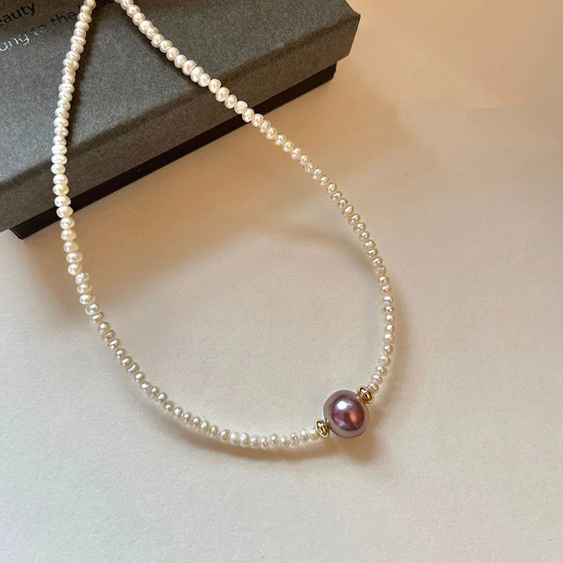 Pink purple freshwater pearl pendant necklace with U-shaped geometric design on a woman