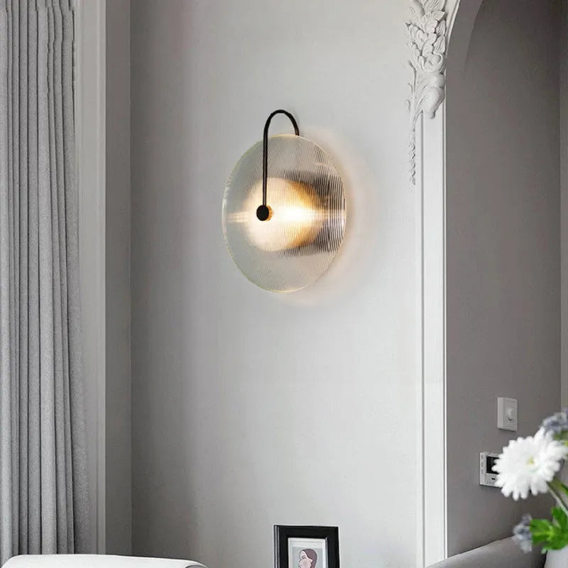 Round glass wall lamp in gold finish mounted on a wall with iron body and clear glass lampshade