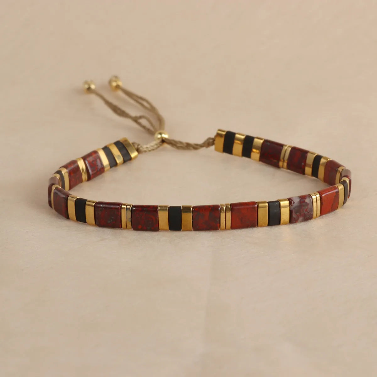 Adjustable geometric beaded bracelet with pull beads in milky white, black, green, blue or red.