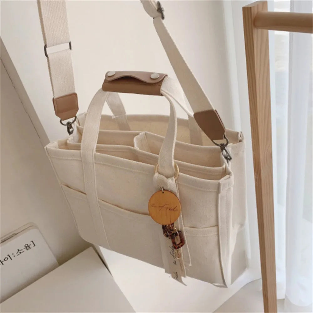 Beige canvas crossbody mommy bag holding baby bottles and wipes on table