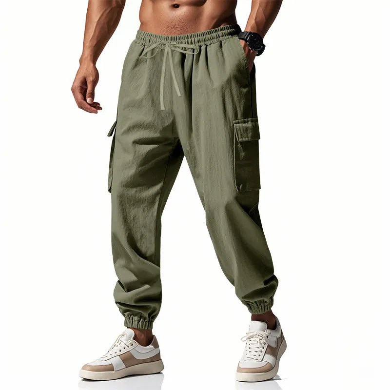 Man wearing loose khaki linen casual trousers with a drawstring waist and ankle-tied legs.