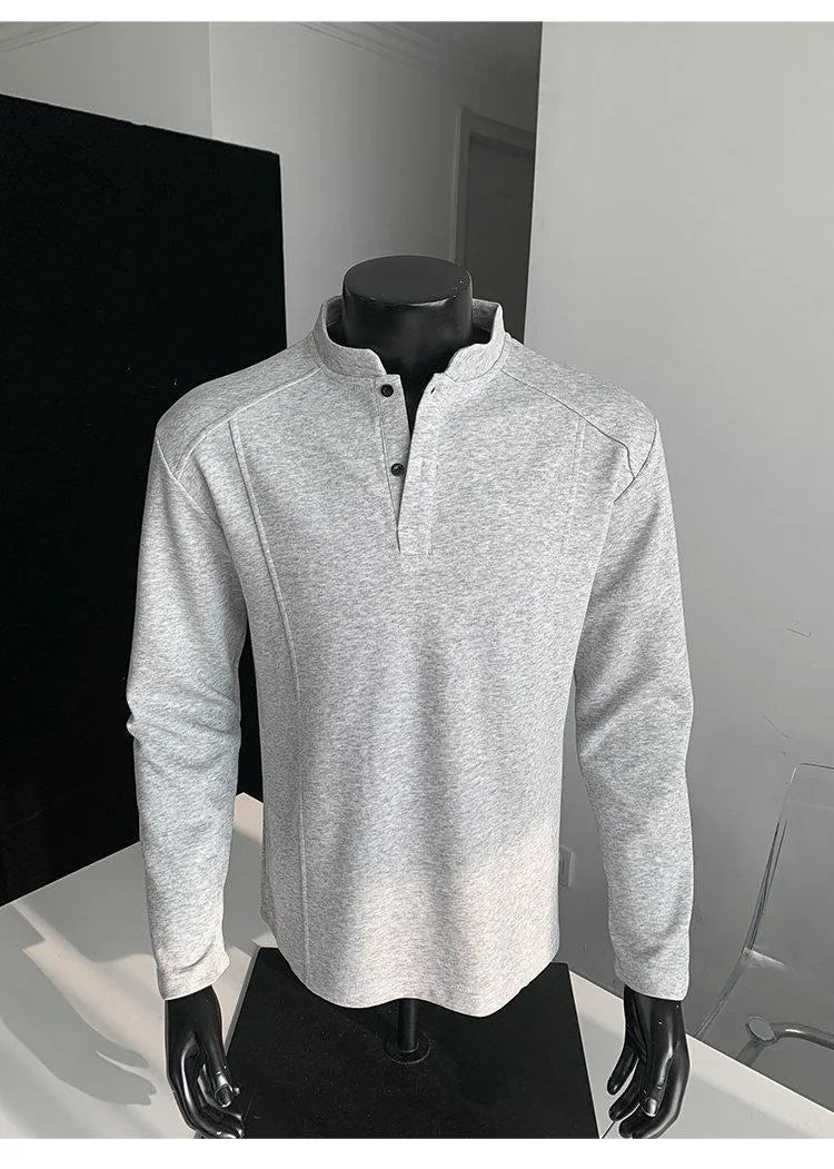 Men's black asymmetric patchwork long sleeve polo shirt with a stand-up collar, laid flat.