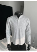 Men's black asymmetric patchwork long sleeve polo shirt with a stand-up collar, laid flat.