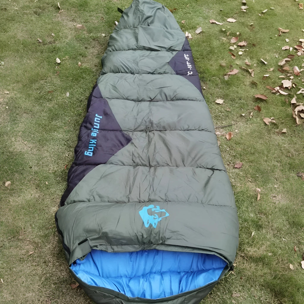 Brown cotton camping sleeping bag rolled next to its grey compression storage bag.