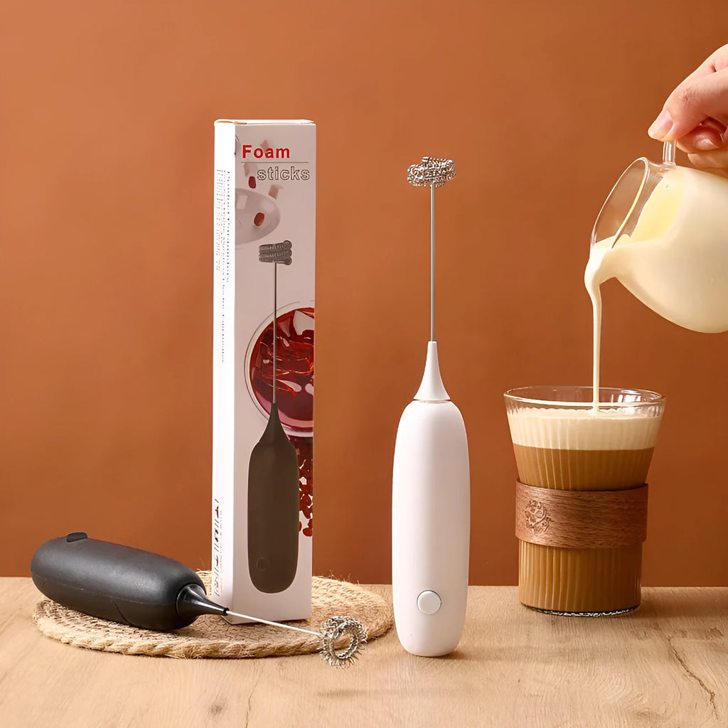Black and white handheld electric milk frother and blender on a kitchen counter.