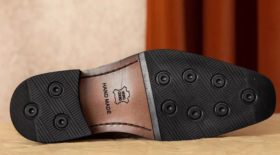 Men's black leather slip-on loafers with a fringed detail on the vamp and a rubber sole.