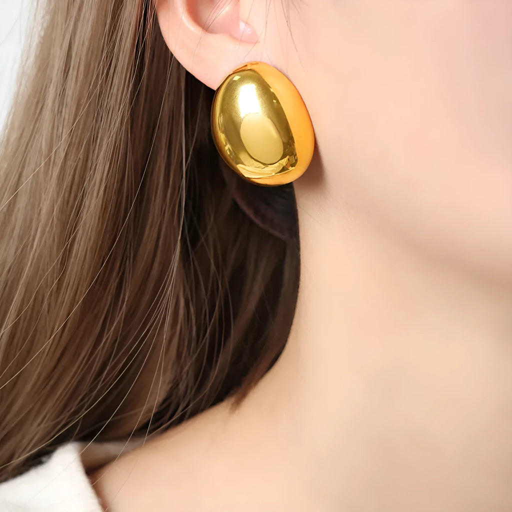 A pair of geometric stainless steel ear studs with an 18K gold plated, glazed surface and line detailing.