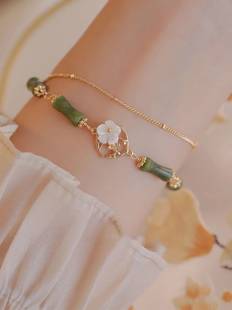 A green olivine stone bracelet with double layers, an Olive Branch charm, and Twin Bells of Ireland pendant.