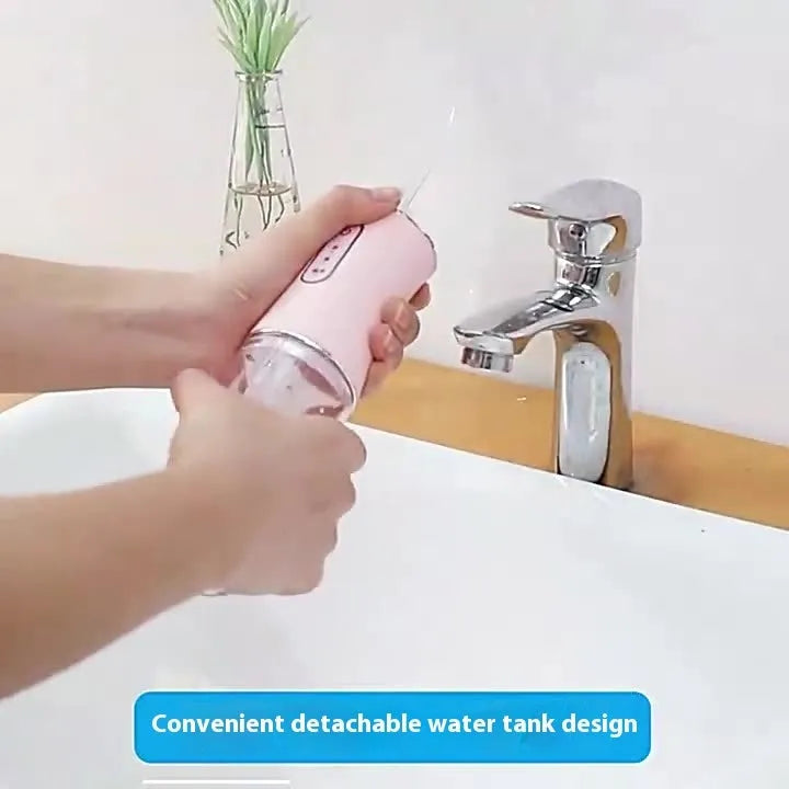 Pink electric water flosser with nozzle and water tank on a bathroom surface