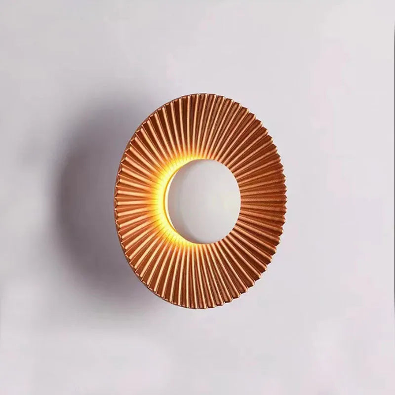 Round wall lamp with aluminium shade in a two-tone white and gold colour combination, mounted on a plain wall.