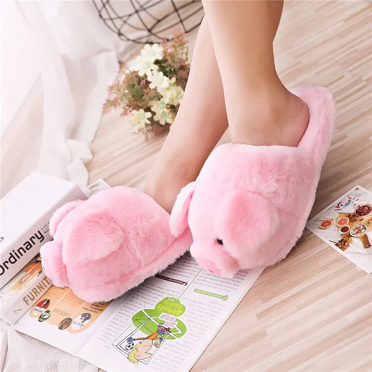 Pink pig-themed plush floor slippers for adults on a plain background.