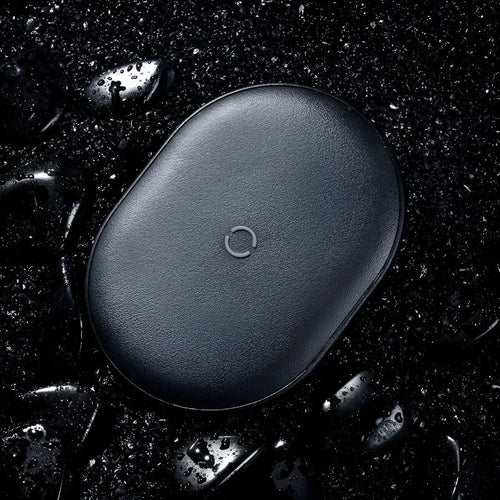 Black Baseus wireless charging pad with a textured surface and a small LED light, next to a mobile phone.