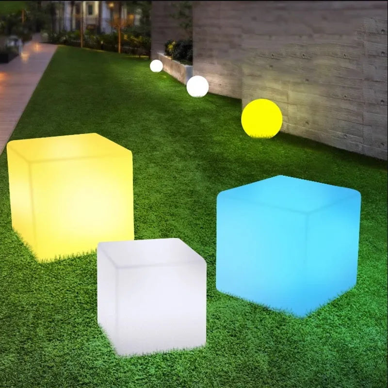 A white, square LED cube light stool with a modern design, shown outdoors on a patio.