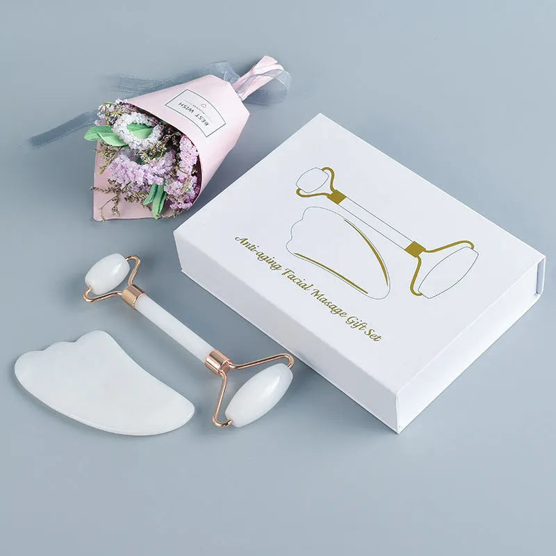 White jade double-headed facial roller and gua sha board set on a flat surface.
