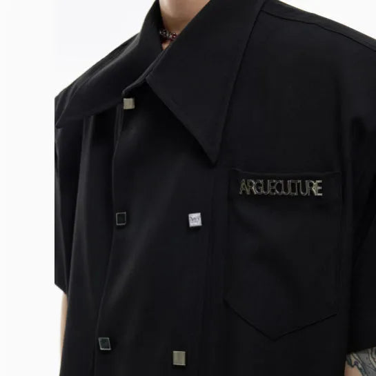 A man's loose-fitting short-sleeved casual shirt in a solid colour with a lapel collar and decorative button details.